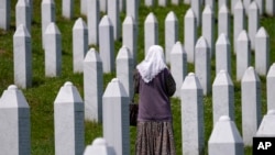 A woman walks among the graves of victims of the Srebrenica massacre at the memorial cemetery in Potocari, near Srebrenica, in eastern Bosnia. 