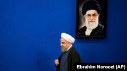 Iranian President Hassan Rouhani walks past a picture of the Supreme Leader Ayatollah Ali Khamenei as he arrives to a press conference at the presidency compound in Tehran, Iran, Monday, April, 10, 2017.