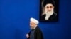 Iranian President Hassan Rouhani walks past a picture of the Supreme Leader Ayatollah Ali Khamenei as he arrives to a press conference at the presidency compound in Tehran, Iran, Monday, April, 10, 2017.