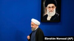 Iranian President Hassan Rouhani walks past a picture of the Supreme Leader Ayatollah Ali Khamenei as he arrives to a press conference at the presidency compound in Tehran, Iran, Monday, April, 10, 2017.