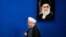 Iranian President Hassan Rouhani walks past a picture of the Supreme Leader Ayatollah Ali Khamenei as he arrives to a press conference at the presidency compound in Tehran, Iran, Monday, April, 10, 2017.