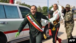 An Iranian soldier carrying an injured comrade at the scene of an attack on a military parade in Ahvaz on September 22.