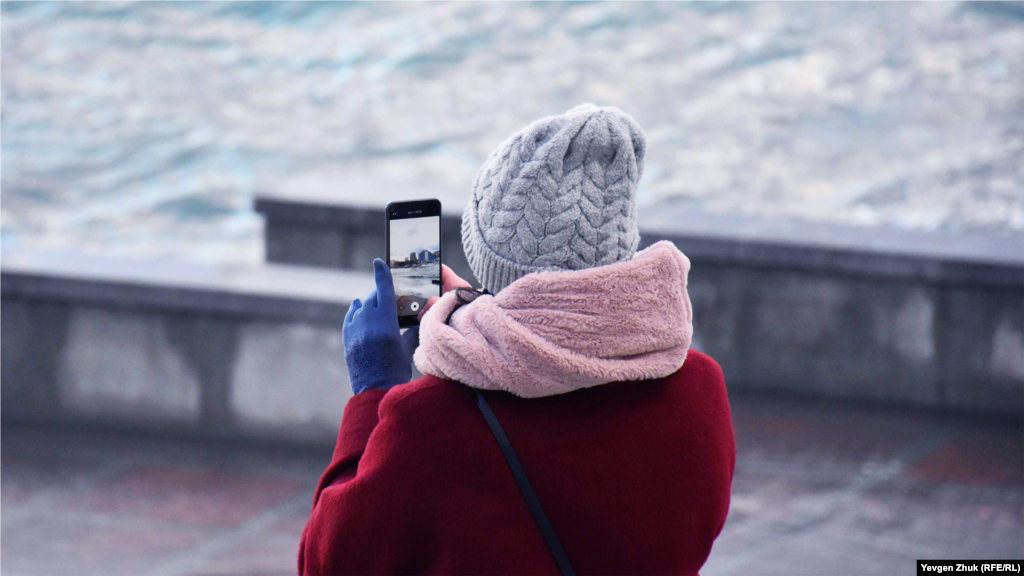 Дівчина фотографує шторм камерою мобільного телефону