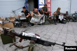 Ukrainian servicemen read newspapers as they rest at a checkpoint near the eastern Ukrainian town of Debaltseve, in the Donetsk region, on August 6.
