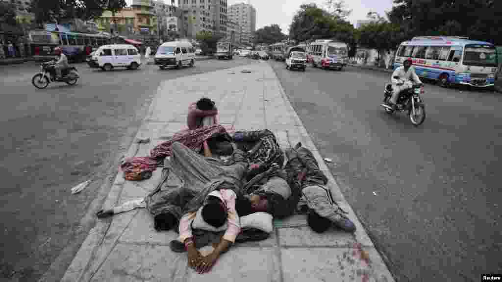 Pakistani youths sleep on a road median early in the morning in Karachi on August 1. (REUTERS/Akhtar Soomro)