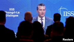 Delegates view a speech by US Defense Secretary Pete Hegseth on a screen at the Shangri-La Dialogue security summit in Singapore on May 30.