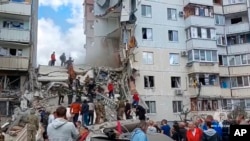Ekipet e shpëtimit duke punuar në vendin e ngjarjes së një ndërtese të shembur pjesërisht nga një sulm raketor në qytetin kufitar Belgorod, Rusi, 12 maj 2024.