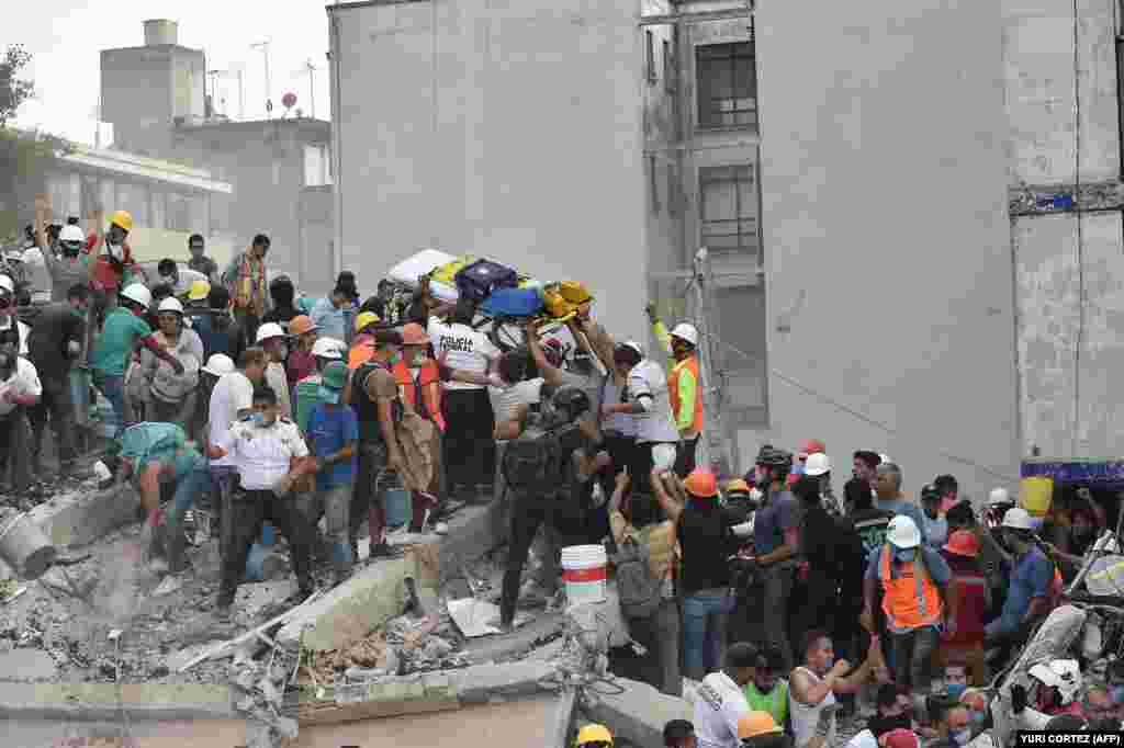 Mexico -- Rescuers, firefighters, policemen, soldiers and volunteers remove rubble and debris from a flattened building in search of survivors after a powerful quake in Mexico City on September 19, 2017. A devastating quake in Mexico on Tuesday killed mor