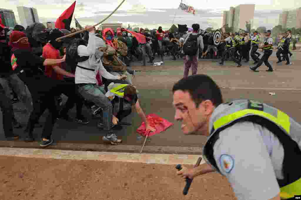 Protesters clash with police during a demonstration on the Ministries Esplanade, the avenue of the main governmental buildings in Brazil's capital, Brasilia, after the Senate passed cuts promoted by the government. (epa/Joédson Alves)