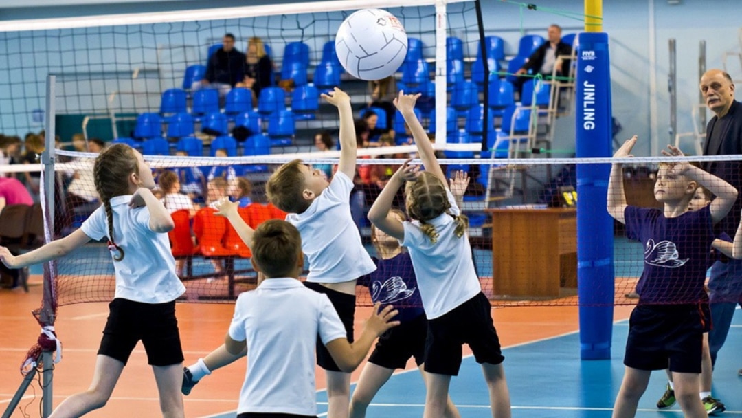 Школярі грають у волейбол біля сітки