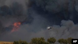 Një helikopter fluturon mes tymit nga një zjarr në Keratea, në periferi të Athinës, të premten, më 8 gusht 2025.