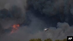 Helikopter leti kroz dim požara u Keratei, predgrađu Atine, u petak, 8. avgusta 2025.