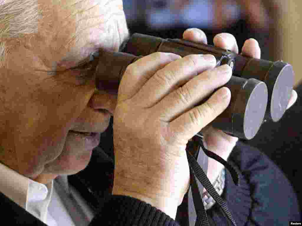 Israel - Israeli Prime Minister Ariel Sharon tries to look through binoculars which still have their lenses caps on near Tel Aviv, January 7, 2003. REUTERS