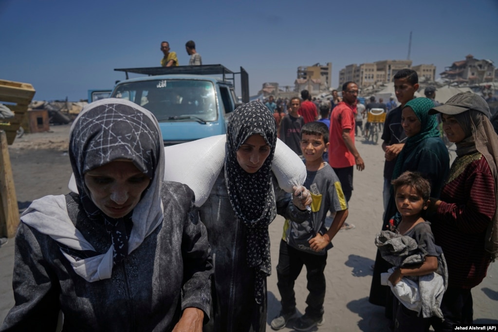Iman Shabat, nënë e pesë fëmijëve, duke bartur një thes me miell, të siguruar nga një karvan ndihmash humanitare, që mbërriti në Qytetin e Gazës nga veriu i territorit, më 22 korrik.