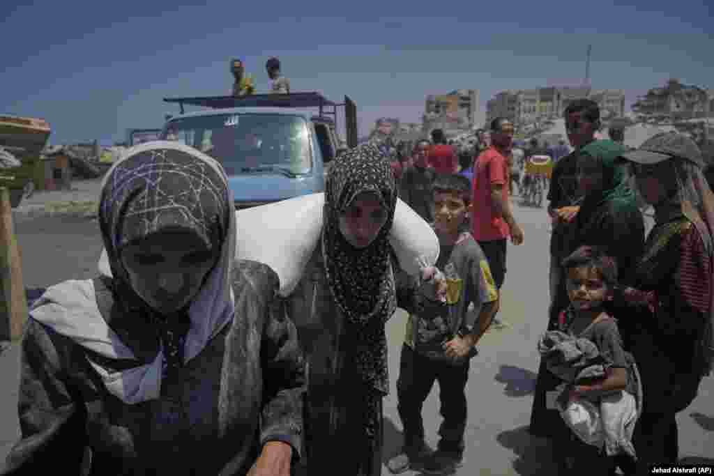 Iman Shabat, nënë e pesë fëmijëve, duke bartur një thes me miell, të siguruar nga një karvan ndihmash humanitare, që mbërriti në Qytetin e Gazës nga veriu i territorit, më 22 korrik.