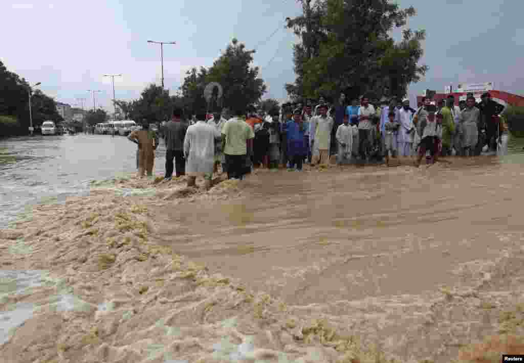 Residents wait to cross a flooded road outside of Karachi on August 4.