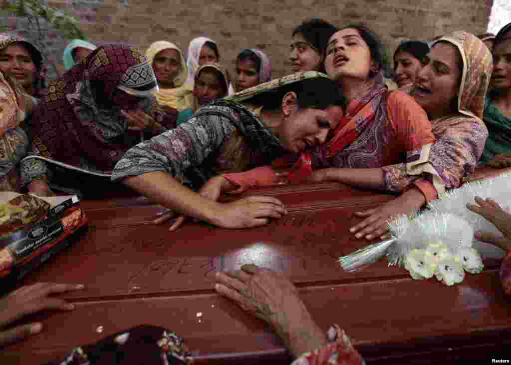 Relatives of one of the 17 children who died after a gas cylinder exploded on a school bus mourn over his coffin on the outskirts of Gujrat, southeast of Islamabad. (Reuters/Faisal Mahmood)