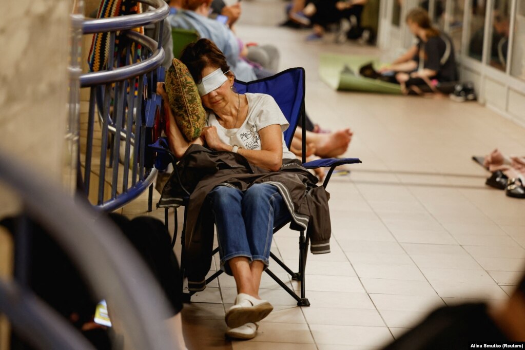 Një grua me sytë e mbuluar për të fjetur, gjatë strehimit në metro, më 8 korrik.