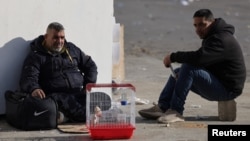 Мъже стоят на улица в Бейрут заедно с част от нещата, които са взели от вкъщи, 6 март 2026 г.