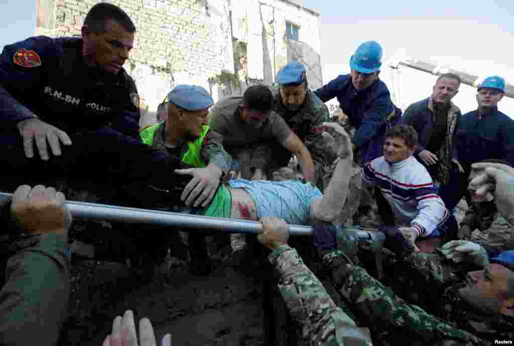 Personeli ushtarak dhe ai i emergjencës shihen duke larguar një person të plagosur nga rrënojat në Thumanë.