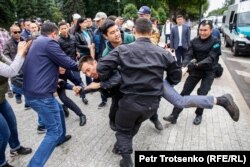 Полицейские несут мужчину к микроавтобусу во время митинга в Алматы, 9 июня 2019 года.