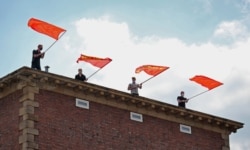 MLPD supporters wave flags featuring the communist hammer and sickle, while crowds sing the Internationale, the socialist anthem, moments after the Lenin monument was uncovered.