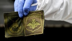 UKRAINE – A Ukrainian forensic expert shows patches found on the body of a Russian soldier exhumed in the village of Zavalivka, west of Kyiv, as the special unit examines a refrigerated rail car stacked with the Russian dead on May 11, 2022