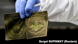  Украински правосъден специалист демонстрира емблеми, открити върху тялото на съветски боец, ексхумирано в село Заваловка, западно от Киев, 11 май. 