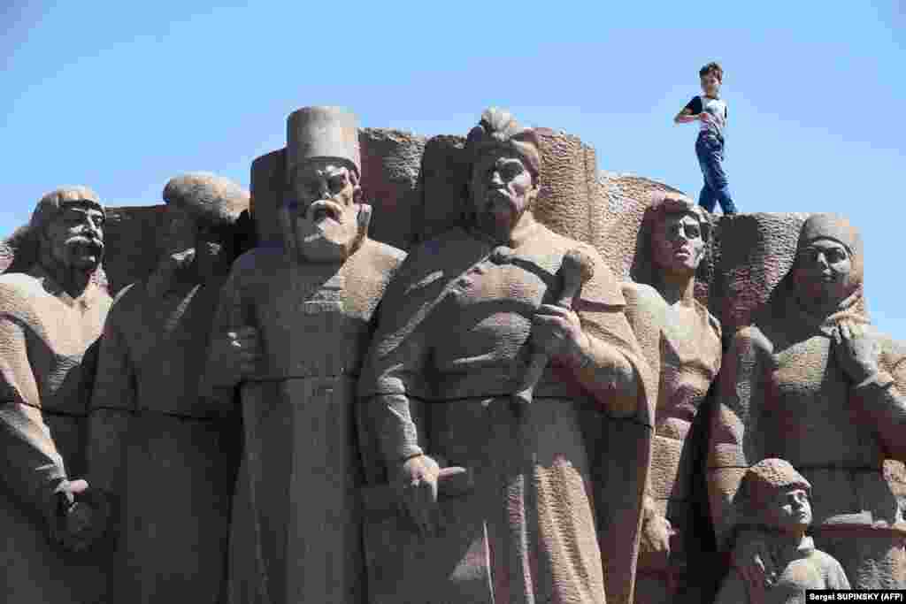 A boy walks on the top of a Soviet-era monument for Ukraine and Russia union in Kyiv. (AFP/Sergei Supinsky)