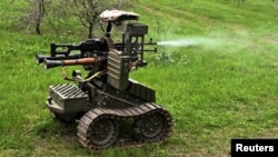 Украинские военнослужащие стреляют из пулемета, установленного на беспилотном наземном роботизированном комплексе, во время испытаний на полигоне вблизи линии фронта. Запорожская область, 10 апреля 2026 года