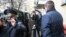 "Белсат" тәуелсіз телеарнасының Минскідегі кеңсесі есігін күзетіп тұрған милиция қызметкері мен жай киімдегі адам.