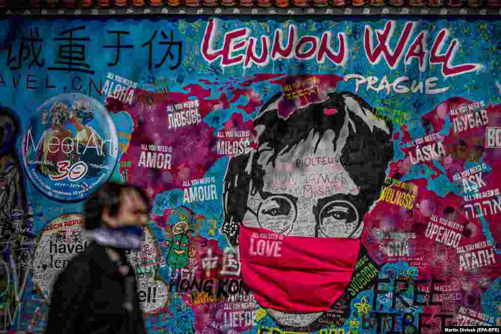 A man wearing a protective mask in the Czech capital, Prague, walks past a memorial wall dedicated to John Lennon, who is depicted as also wearing a face mask. (epa-EFE/Martin Divisek)