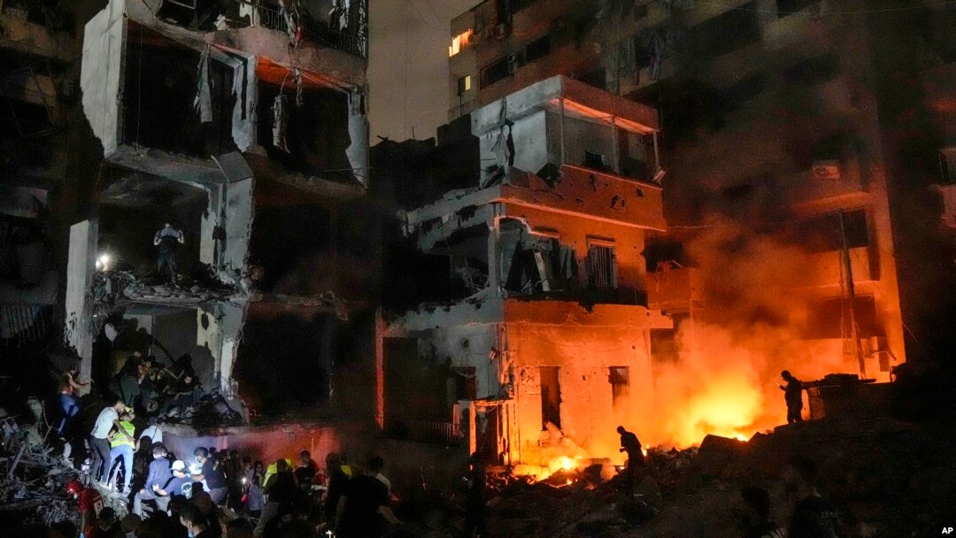 Oameni adunați în fața unor clădiri distruse de un atac cu bombe, al Israelului, în Beirut, capitala Libanului.