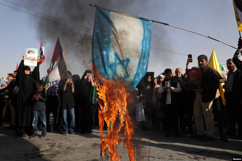 Iranians burn a painted Israeli flag during a gathering in Tehran to support Iran's October 1 attack on Israel.