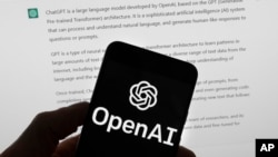 OpenAI logo se vidi na mobilnom telefonu ispred ekrana računara koji prikazuje rezultate četbota ChatGPT-a, 21. marta 2023, u Bostonu. 