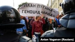 Митингующие с плакатом «План Путина – геноцид народа» перед полицейскими, которые блокируют улицу во время митинга против повышения пенсионного возраста. Санкт-Петербург, 9 сентября 2018 года
