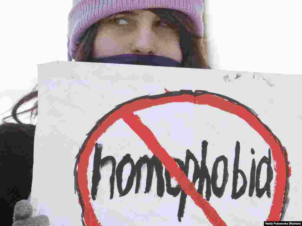 A gay-rights activist in Belarus looks out from behind a placard during the first-ever sanctioned Gay, Lesbian, and Bisexual Pride rally near the Department of Justice in Minsk on February 14, 2011.