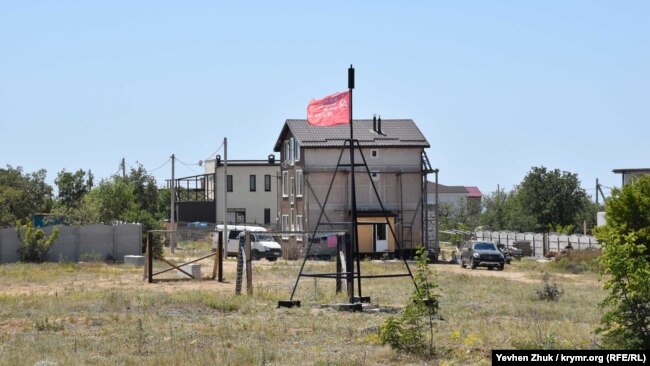 На геодезическом знаке триангуляционного пункта вывешен красный флаг с наименованием воинской части времен войны
