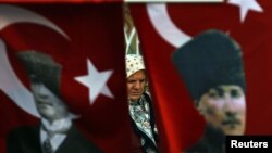 A woman wearing a traditional head scarf is framed by Turkish flags depicting the founder of modern Turkey in Istanbul. (file photo)