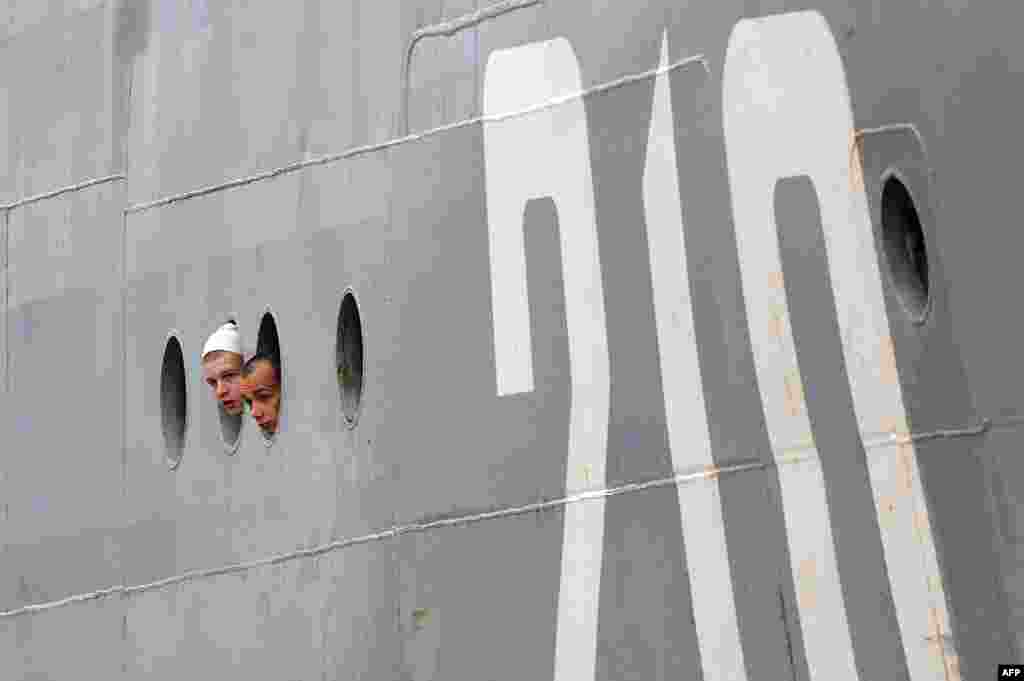 Russian sailors look through the porthole as they arrive aboard the &quot;Smolny&quot; in Saint-Nazaire on June 30. (AFP/Jean Sebastien-Everard)