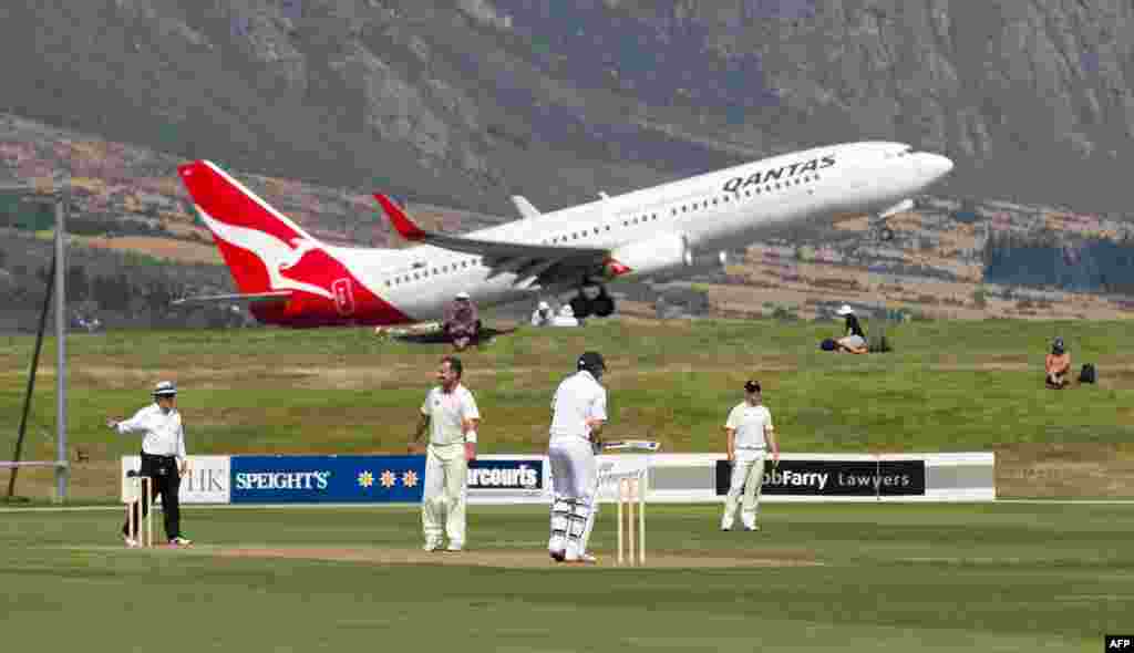 A Qantas jet takes off above the cricketers during the first day of the four-day warm-up international cricket match between New Zealand and England in Queenstown, New Zealand. (AFP/Marty Melville)