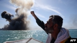 Iran -- A member of Iran's elite Revolutionary Guards chants slogans after attacking a naval vessel during a military drill in the Strait of Hormuz in southern Iran, February 25, 2015