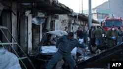 Afghan police and security personnel inspect the scene of a suicide car bomb attack in Kabul on April 10. 