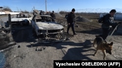 Police walk past a burnt out vehicle in Kazakhstan's Zhambyl region after an outbreak of violence that claimed several lives earlier this month. 