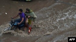 Pakistani residents travel through floodwaters following heavy rain in Lahore on July 14.