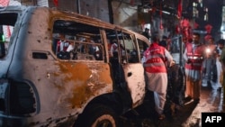 Pakistani volunteers search a destroyed vehicle at the site of a suicide bomb attack at an election campaign rally in Peshawar on April 16.