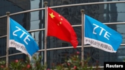 China -- A Chinese national flag and two flags bearing the name of ZTE fly outside the ZTE R&D building in Shenzhen, April 27, 2016