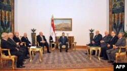 Президент Мухаммед Мурси (төрдө) вице-президент Махмуд Мекки (оңдон бешинчи), юстиция министри Ахмед Мекки (оңдон төртүнчү) менен бирге Соттордун Жогорку кеңешинин мүчөлөрү менен кездешүүдө. Каир, 26-ноябрь, 2012