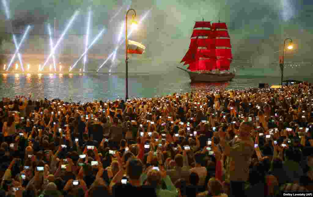 People watch a ship sailing on the Neva River during the Scarlet Sails festival marking school graduation in St. Petersburg on June 24. (AP/Dmitri Lovetsky)