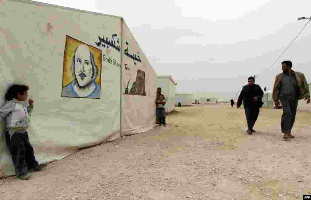 Syrian refugees walk past the &quot;Shakespeare tent&quot; where children are rehearsing &quot;King Lear&quot; in the Zaatari refugee camp in Jordan. &nbsp;